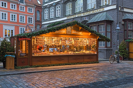 LUNEBURG, GERMANY - DECEMBER 6, 2018: Market stall with Christmas gingerbreads, roasted almonds and sweets at Am Sande square close to historical building that houses Chamber of Commerce and Industry.のeditorial素材