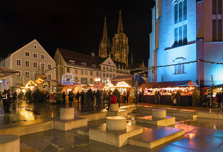 REGENSBURG, GERMANY - DECEMBER 13, 2019: Christmas market at Neupfarrplatz (New Parish Square) close to Neupfarrkirche (New Parish Church). Towers of Regensburg Cathedral are visible in the backgroundのeditorial素材