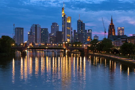 FRANKFURT-AM-MAIN, GERMANY - MAY 11, 2018: Evening view from a bridge across the Main to skyscrapers of financial district. Tower of the Frankfurt Cathedral is visible on the right.のeditorial素材