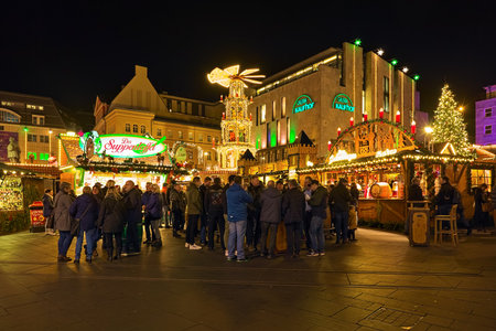 HALLE AN DER SAALE, GERMANY - DECEMBER 17, 2019: Christmas market on Market Square in dusk. Many unknown people stand next to the market stalls with food and Christmas drinks.のeditorial素材