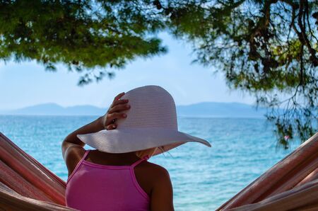 girl with a hat in a hammock on the beachの写真素材