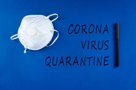 Face mask and black marker with Corona Virus  Quarantine written on blue background in a conceptual image of public health threatening virus.の写真素材