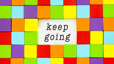 Keep Going typed on white paper surrounded by colourful blocks in a conceptual image of inspiration and motivation.の写真素材