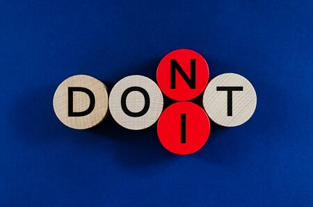 Conceptual image of word Dont spelled on wooden pegs with second to the last circle replacing to spell the word Do It.の写真素材