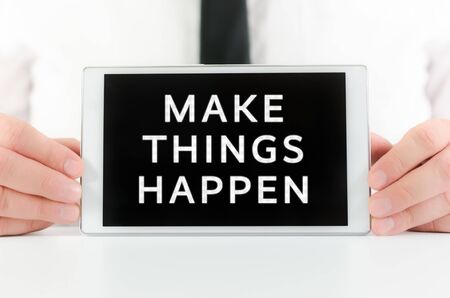 Businessman holding a smart tablet with sign Make things happen on screenの写真素材