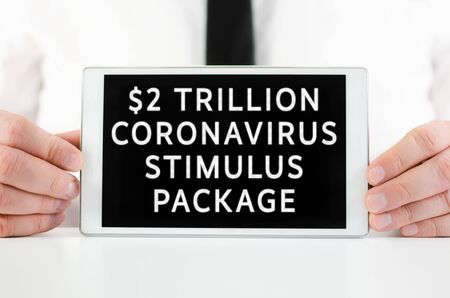 Businessman holding a smart tablet with sign  $2 Trillion coronavirus stimulus package in response to the impact on the economy and crisisの写真素材