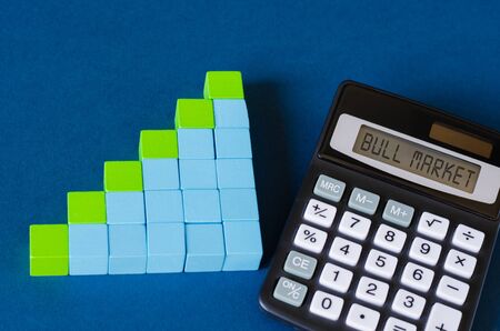 Blue and green cubes assembled in growing column graf and calculator with Bull Market written on screenの写真素材