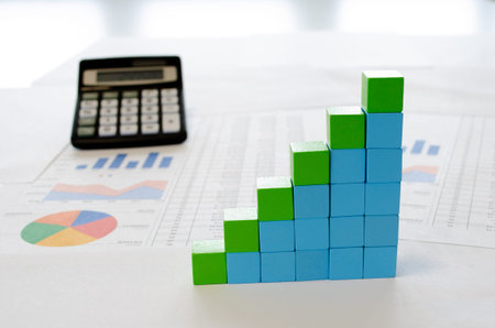 Financial documents, with blue and greencubes arranged in a column graph as a concept for growth ,...