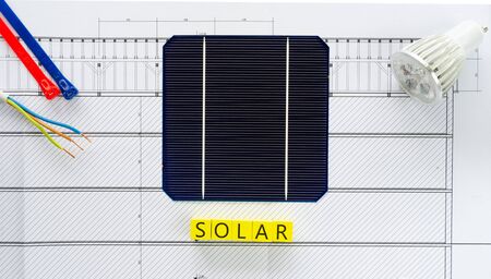 Word solar written on yellow wooden blocks with solar cell, led bulb and cable in  a conceptual image for solar power generation. Top view over blueprints.の写真素材