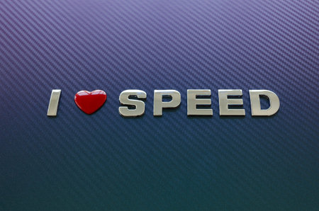 Concept of love of speed, fast cars, motoracing. Letters on carbon fiber background