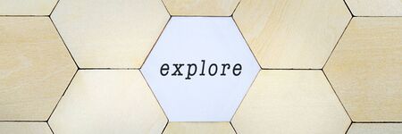 Wooden hexagon missing from puzzle, revealing the word explore in a conceptual image of exploring and discoveryの写真素材