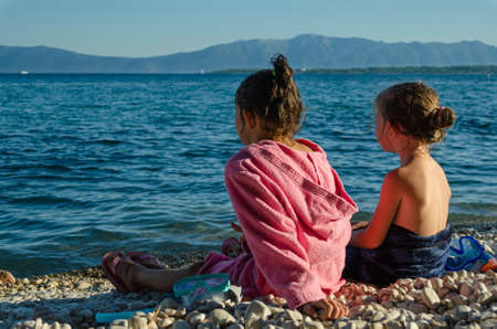 Sisters sitting by the sea after swimmingの写真素材