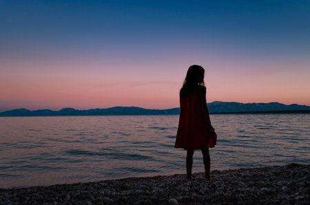 Silhouette of a young girl standing on a beach