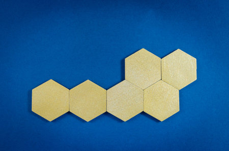 Six gold wooden hexagons with copy space in a conceptual image. Over blue background.の写真素材