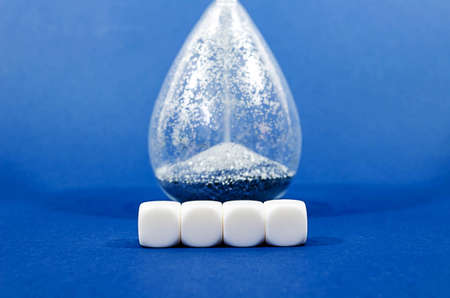 Four blank white blocks in front of  running hourglass  in a conceptual image. Side view, over blue background.の写真素材