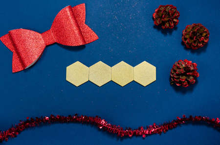 Gold wooden hexagons with copy space and red bow, cones and girland in a  conceptual image of the coming new year. Over blue background.の写真素材