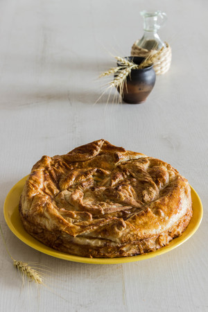 Homemade pie covered with apples, cinnamon, foxberry and nuts on the white wood tableの写真素材