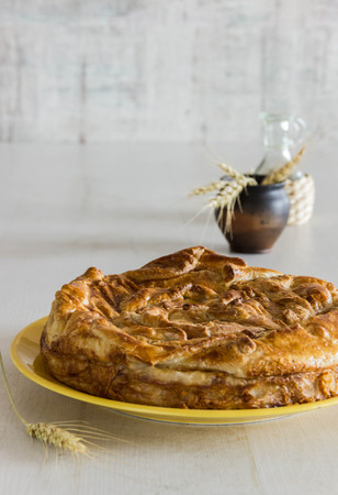 Homemade pie covered with apples, cinnamon, foxberry and nuts on the white wood tableの写真素材