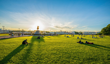 St. Petersburg, Russia 06-14-2021Residents of the city and tourists relax sitting on the lawn in the Alexander Garden in the rays of the setting sun during the white nightsのeditorial素材