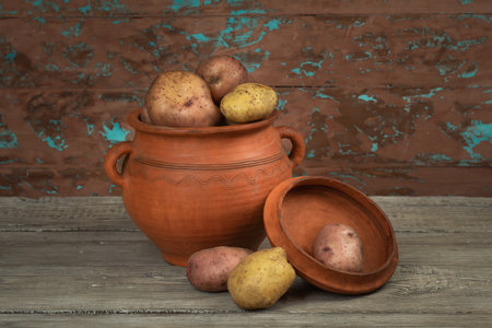 Potatoes in rustic pottery on the background of a wall with peeling paintの写真素材