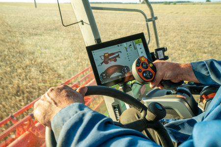 the machine operator at the helm of a modern combine harvester harvests grainの写真素材
