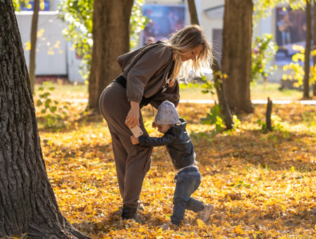Happy mother and child playing in the autumn park
