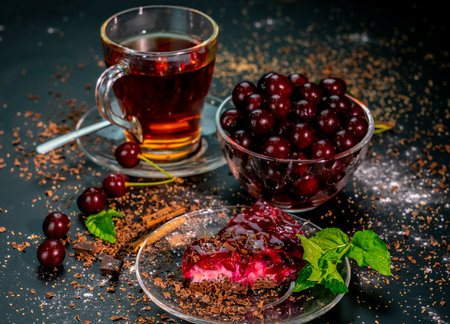 still life with a Cup of strong tea, ripe cherries and cherry cake on a black background.の写真素材