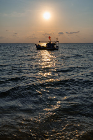 Fishing boat under the flag of Vietnam in the South Sea against the sunsetの写真素材