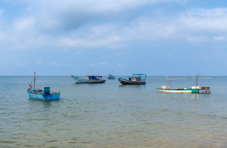 The coast of the tropical sea with fishing boats parked near the shoreの写真素材