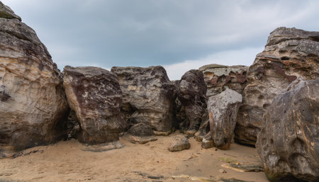 Massive rocks with weathered surfaces and unusual shapes under a gray sky, evoking an ancient world of natureの写真素材