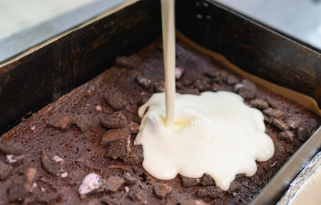 Making a cake, pouring mousse into a chocolate sponge cake with cookie crumbsの写真素材
