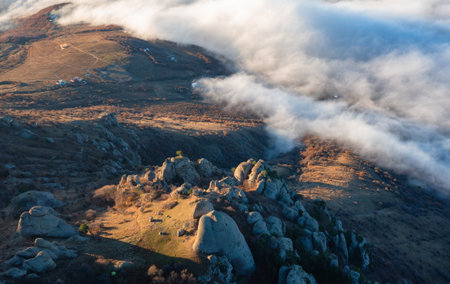 Panoramic view of a mountainous landscape with clouds spreading over villages at sunsetの写真素材