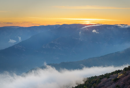 Misty mountains and clouds create a magical atmosphere against the dawn lightの写真素材