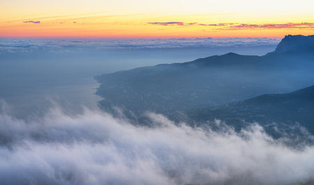 Fog drapes over the valley, creating a serene panorama of the mountain landscapeの写真素材