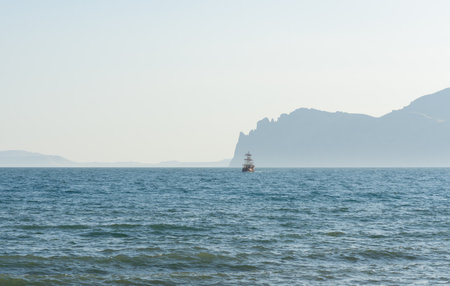 Historic sailing ship at sea near mountain foothillsの写真素材