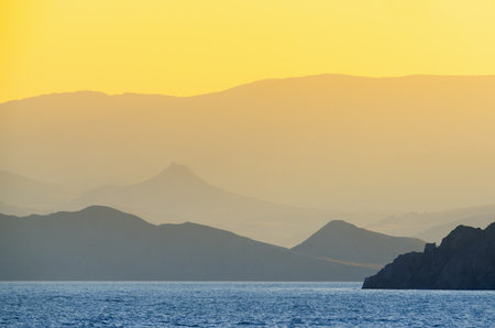 Soft silhouettes of mountains against a golden skyの写真素材