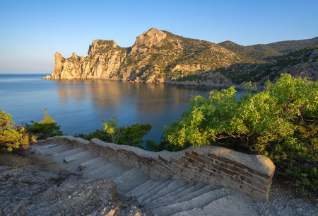 Stone path among mountains and greenery overlooking the calm bay of Novy Svet, Crimea