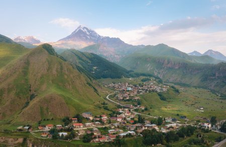 Picturesque mountain landscape of Georgia with village and snow-capped Kazbek.