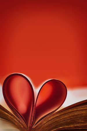 Abstract background with red accent. Old book. An open book with a heart folded from folded sheets. Love education concept. Abstract blurred hearts background from book pages.Copy spaceの写真素材