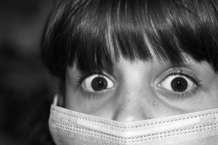 Fear of being infected with the Covid-19 corona virus.Large portrait of a child with brown eyes and a protective medical mask on his face.の写真素材