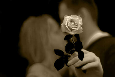 Blurred background photo of a young romantic couple. A hand in a protective glove holds a rose. Love in the face of the coronavirus. Valentine's day and coronavirus.Love and coronavirusの写真素材