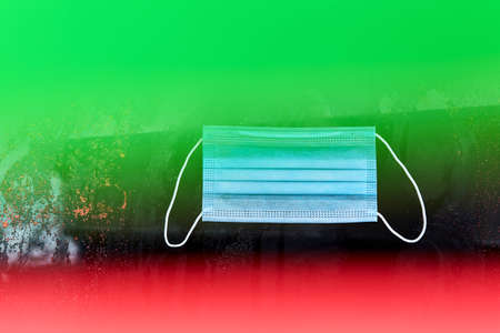 Disposable mask to prevent the spread of viruses and protect against Covid-19. Red and green quarantine area. Soft focus.の写真素材