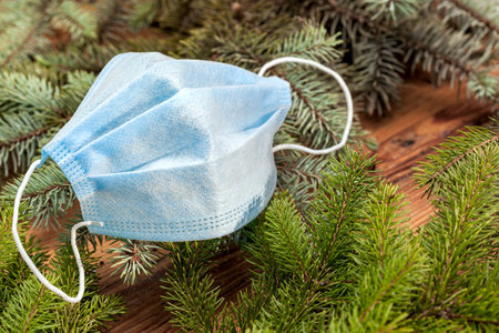 Christmas background in the era of virus. A new concept for a normal Christmas. Spruce branches and a medical mask. Copy space.の写真素材