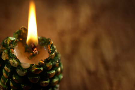 Hot candle in the shape of a Christmas tree. Christmas background with free space of a neutral tone.