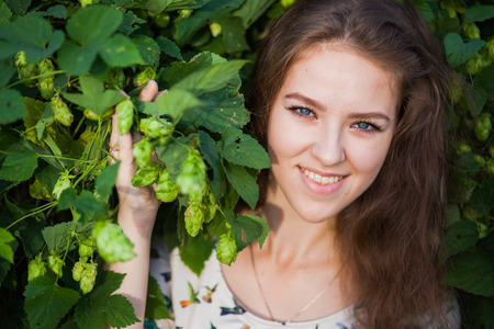 Young beautiful girl in fresh green branches of hop, closeup portrait, eloquent eyes, copy space for textの写真素材