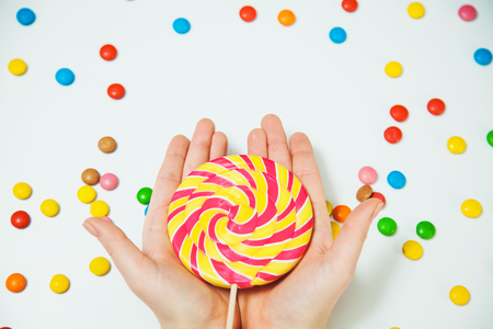 Chocolate Candy pattern Lollipop in Hand White Background Lay Flat top view minimal design Giving Gesrture concept copy spaceの写真素材