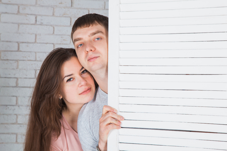 Beautiful loving couple behind the folding screen. Standing close to each other.  Copy spaceの写真素材