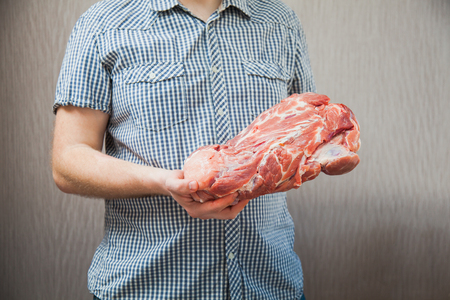 Huge piece of pork neck in male hands. Man holding meat. Dinner preparingの写真素材