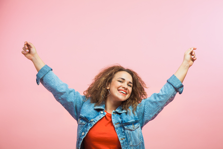 Young woman in jeans coat freedom and happiness. Positive feelings and emitions, copy space, pink backgroundの写真素材