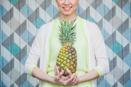 Freah young woman with juicy sweet pineapple. Pretty girl holds ananas and smile. Summer and fruitsの写真素材